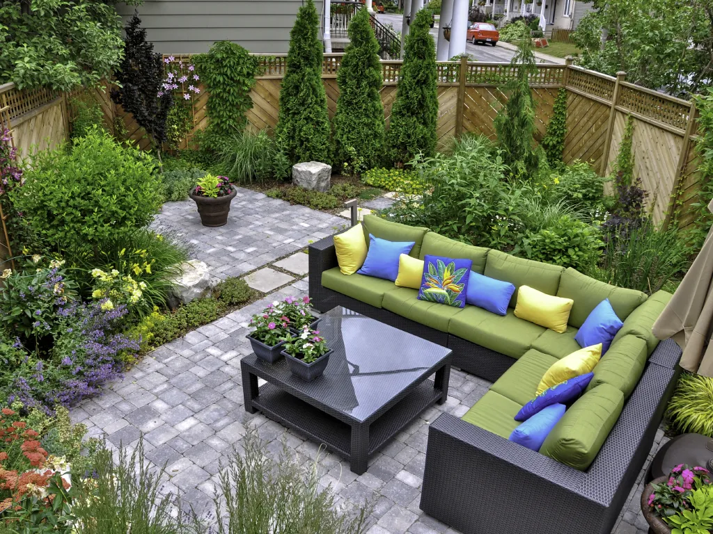 GettyImages-1452751854 Lush backyard with green sectional sofa.